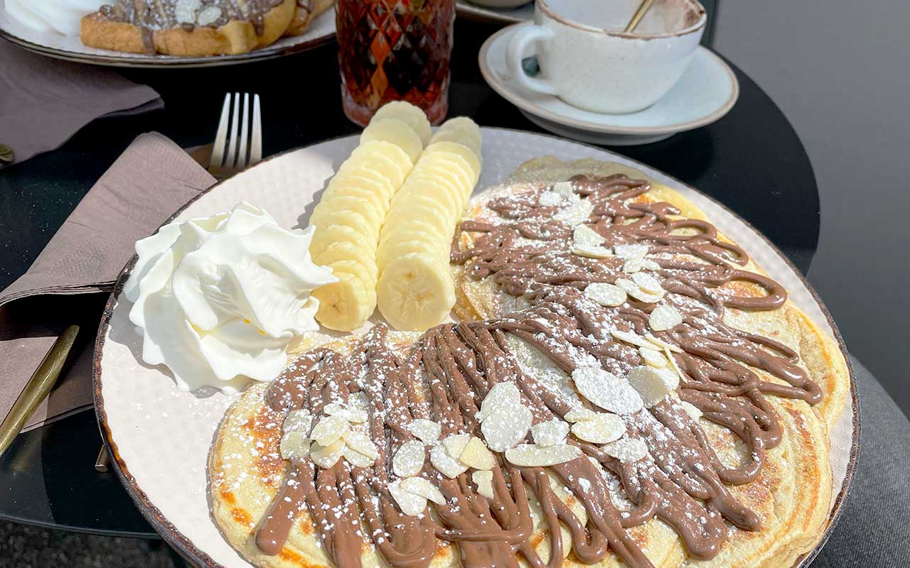 Pancakes with chocolate sauce, whipped cream and sliced bananas